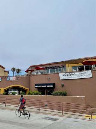 A cyclist pedalling outside Amplified taproom at Pacific Beach