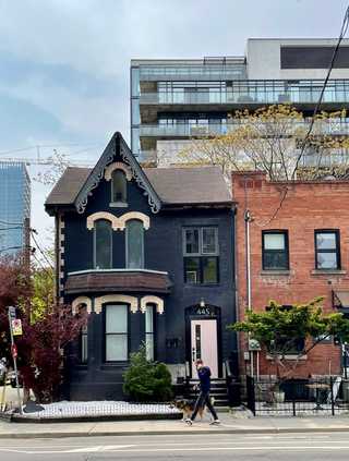 An old black decorative house against modern apartments