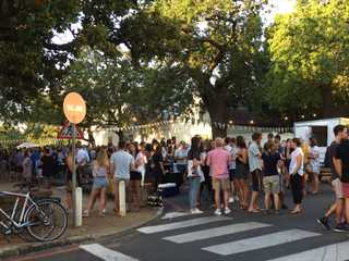 People crowding the street enjoying streetfood and beer