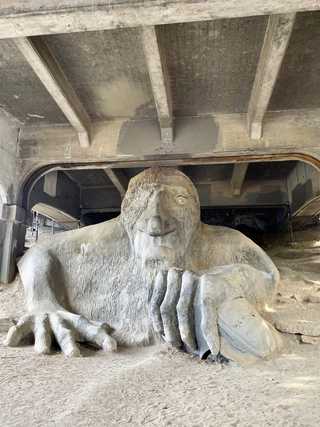 A massive troll sculpture under a bridge