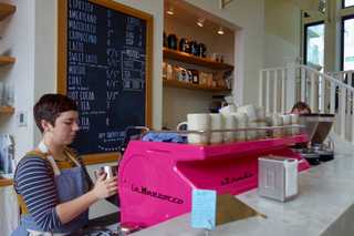 Barista busy making coffees on bright pink La Marzocco coffee machine