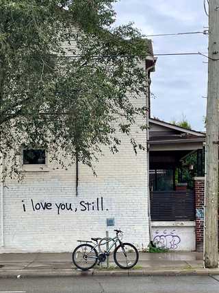 A black graffiti saying I love you still on a whitewashed house