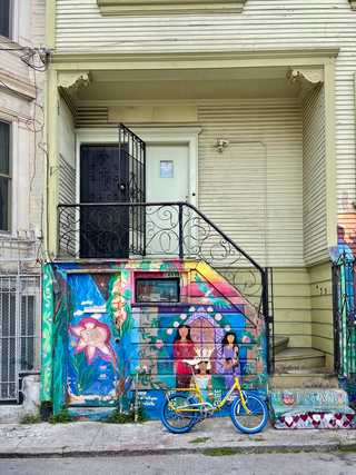 A colourful bike leaning against a Latin influences graffiti