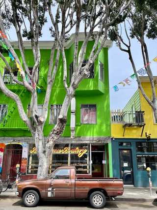 An old car in front of a bright green Mexican bakery