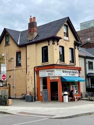 A girl sitting in front of a humble convenience store