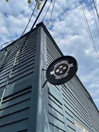 A modern sign of a camera shop agains a grey wooden house