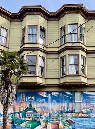 A Victorian wooden apartments with a colourful mural on side